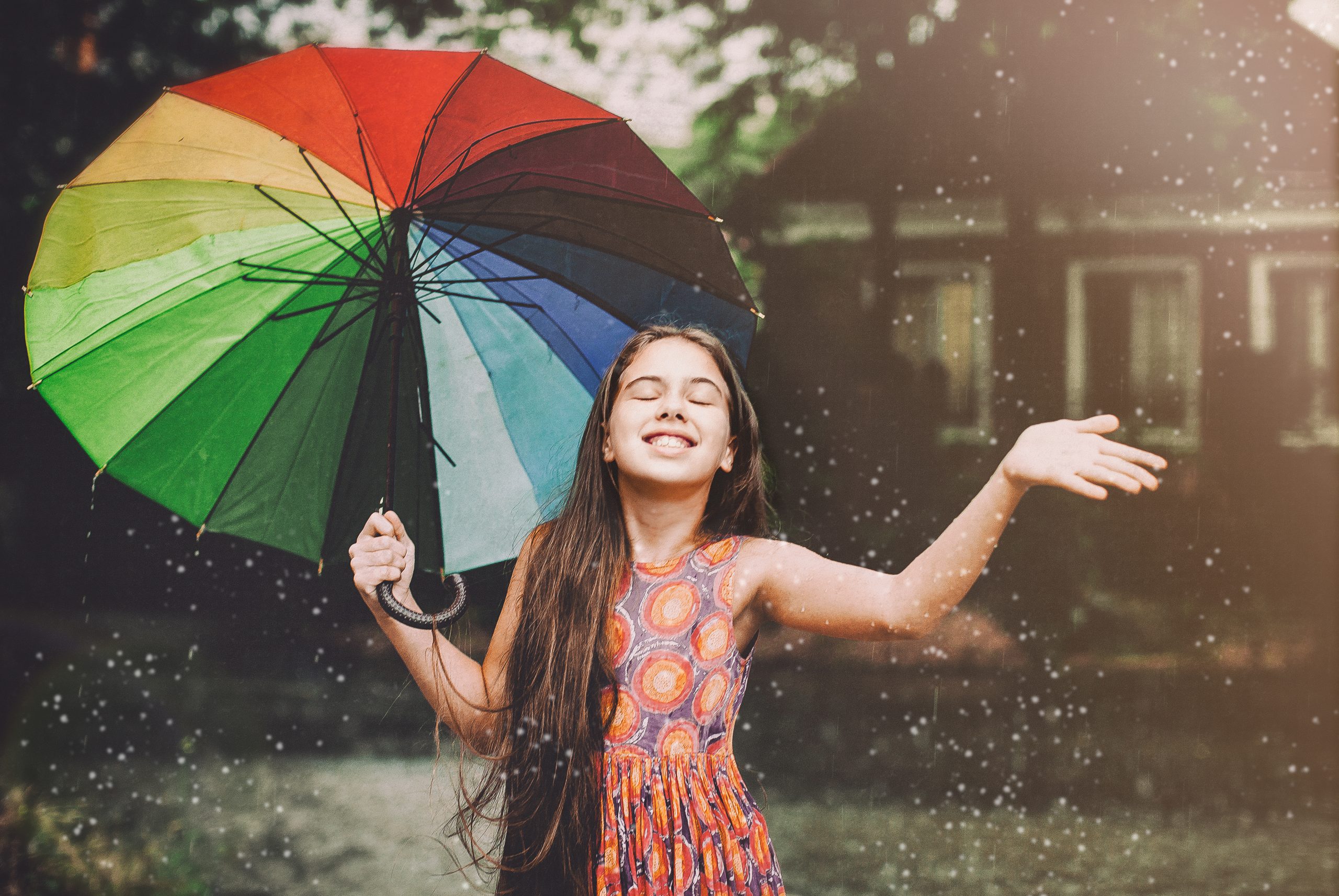 junge Frau mit Regenschirm allen Farben des Regenbogens im Regen